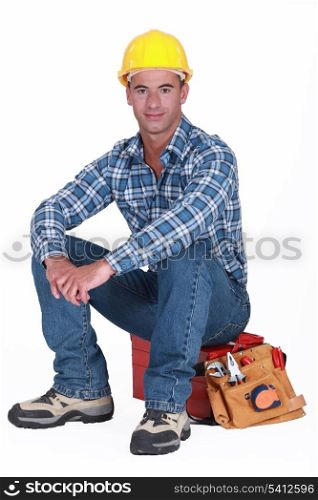 A construction worker sitting on his toolbox.