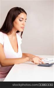 A content women calculating her finances at a desk with money and a calculator