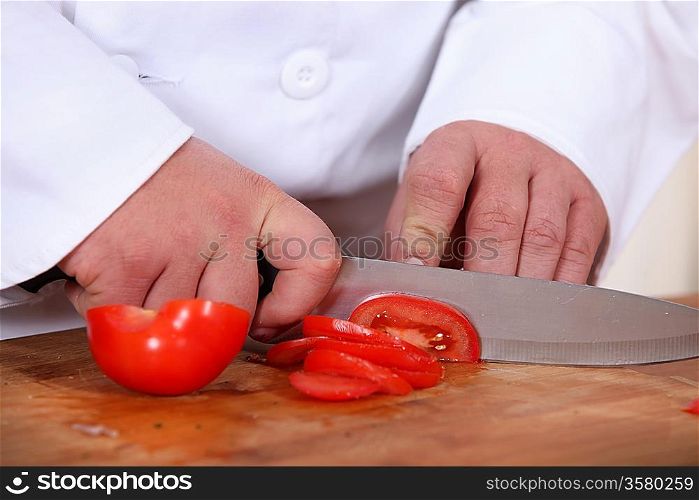 A cook slicing a tomato