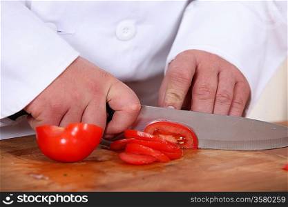 A cook slicing a tomato