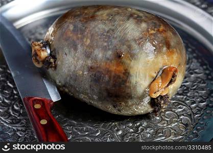 A cooked haggis on an ornate metal tray, such as might be used for a Burns&acute; Supper, with a knire