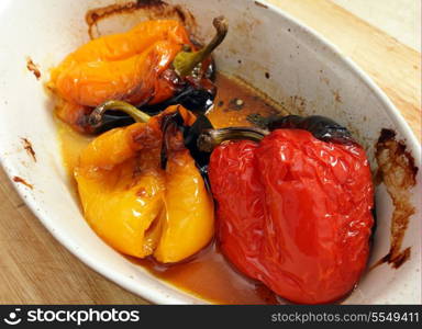 A cooking bowl with roasted yellow, orange and red sweet peppers.