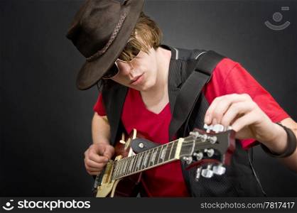 A cool looking guitar player tuning his instrument