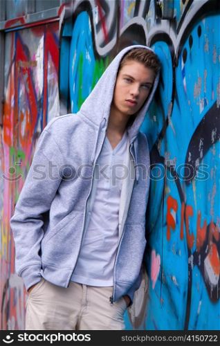a cool-looking young man in front of graffiti