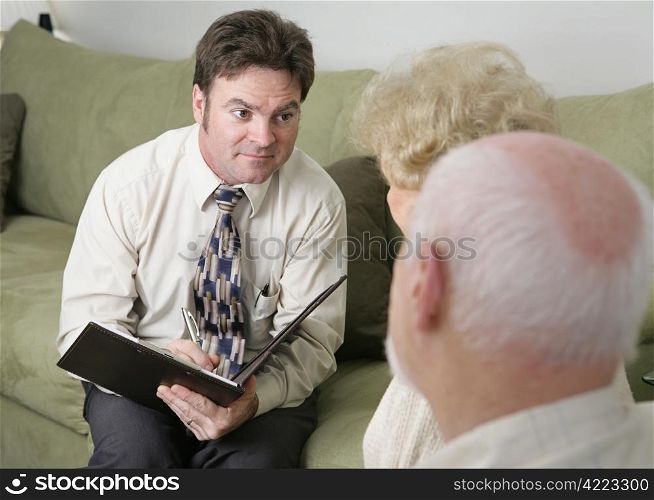A counselor with a caring expression sitting across from an elderly couple.