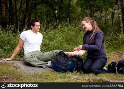 A couple camping and putting on a leg bandage