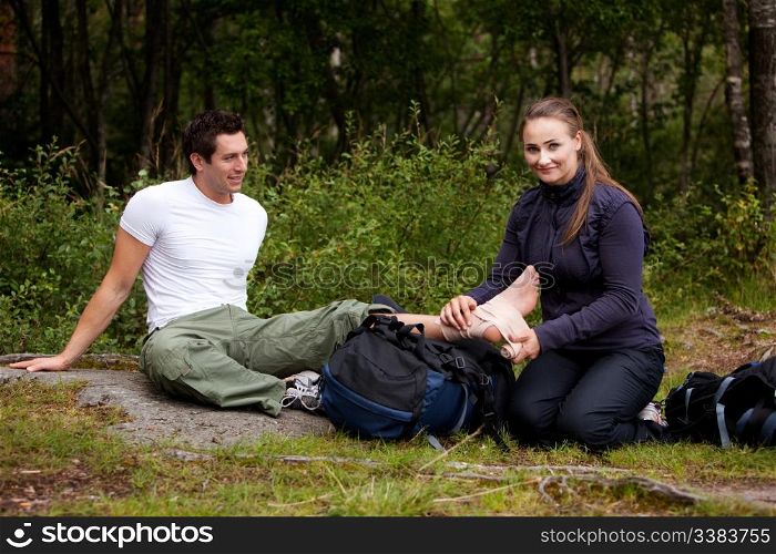 A couple camping and putting on a leg bandage