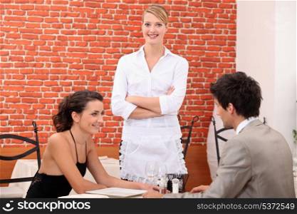 a couple dining at a restaurant and a waitress crossing her arms