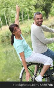 a couple doing bike in the country, the woman is doing airplane with her arms