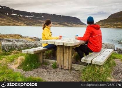 A couple drinking tea close to a beautiful lake