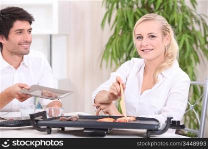 a couple eating food cooked with an electric plancha