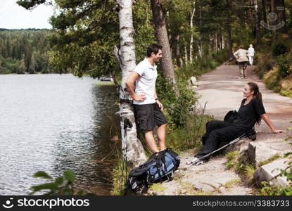 A couple hiking in the woods taking a break by the lake