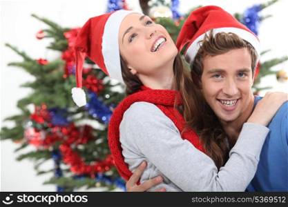 a couple hugging in front of a Christmas tree