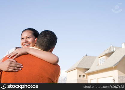 A couple hugging outside their new home