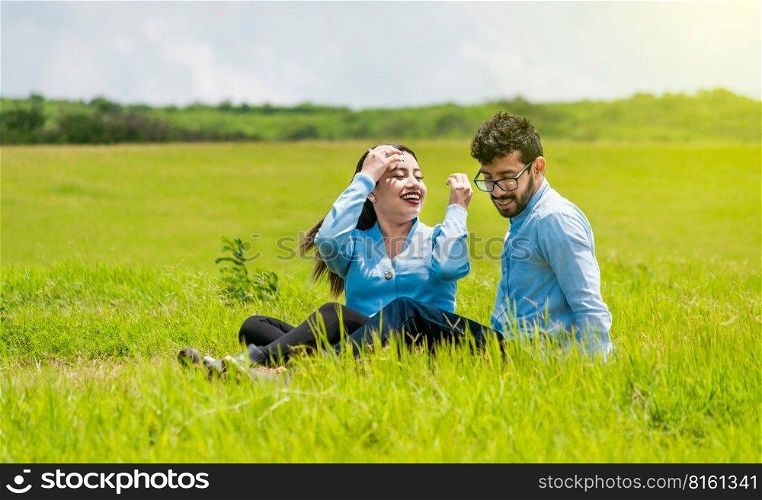 A couple in love sitting in the field, Romantic couple sitting on the grass outdoors, Smiling teenage couple sitting on the grass on a sunny day