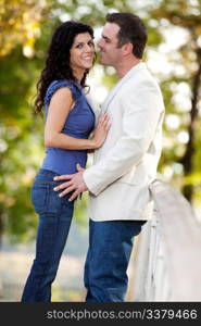 A couple in the park with the man smiling at the woman