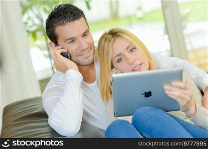 a couple is using a phone and ipad