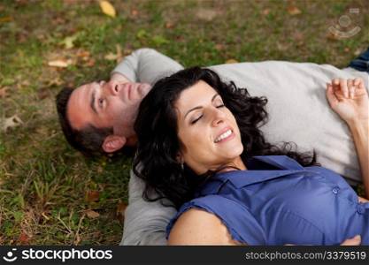 A couple laying on grass in a park daydreaming. Focus on the womans eyes