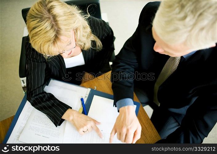 A couple (male/female) of businesspeople working on a file (very shallow depth of field)