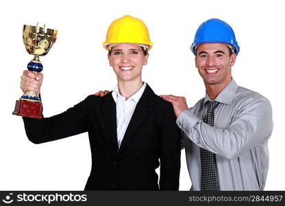 A couple of architects holding a trophy.