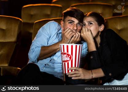 A couple of lovers watching movie shock and eyes close in the movie theater cinema.
