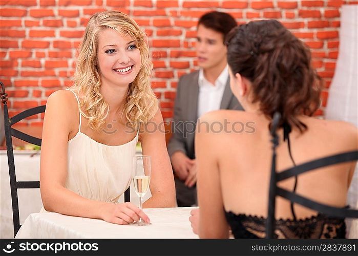 A couple of women drinking champagne in a restaurant.