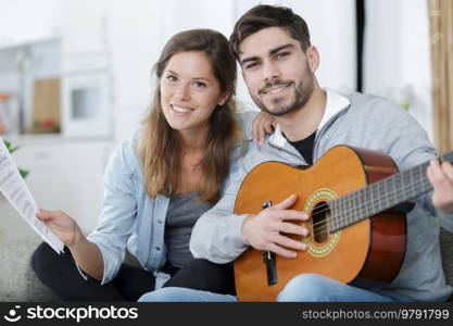 a couple playing guitar on couch indoor