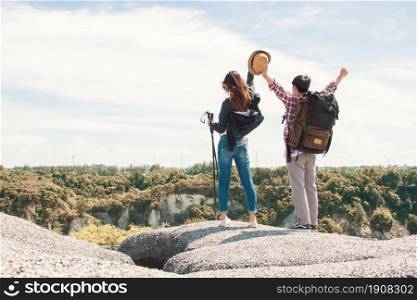 A couple raising their hands after climbing, hiking successfully to the top or peak of mountains. Travel and Summer Concept.
