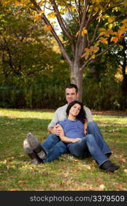 A couple relaxing in the park by a tree