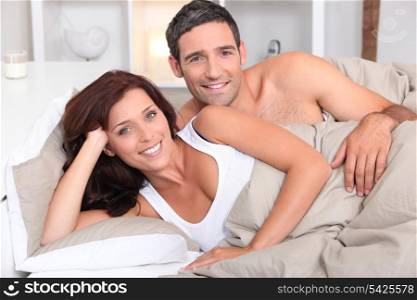 a couple reposing in bed in the morning