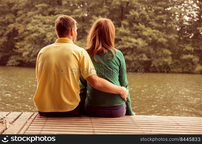 a couple sitting by the water and hugging