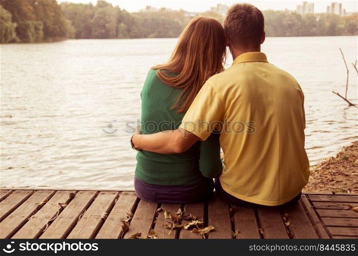 a couple sitting by the water and hugging