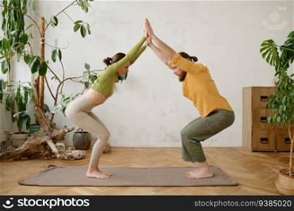 A couple training yoga in pair doing acrobatic plank together. Millennial man and woman making balancing exercise. A couple training yoga in pair doing acrobatic plank together