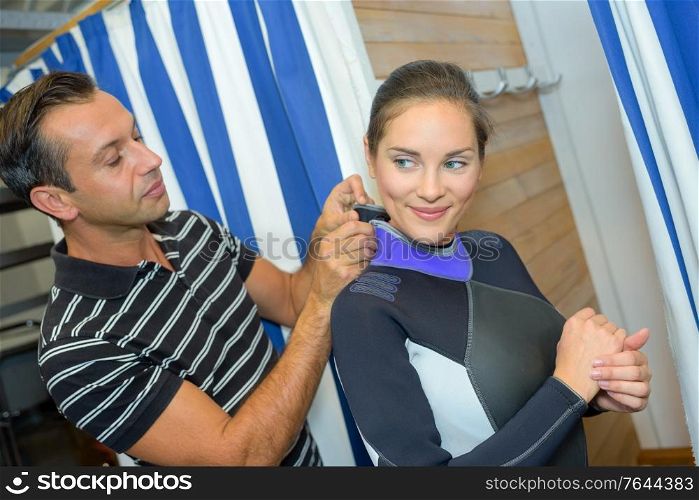a couple trying on a wetsuit