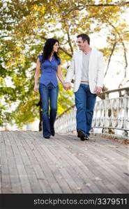 A couple walking on a bridge in a park