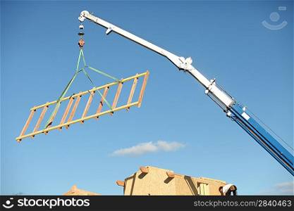 A crane lifting a wood structure.