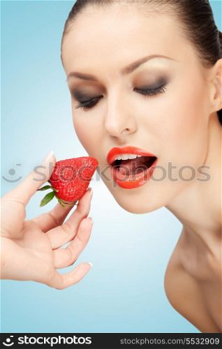 A creative portrait of a beautiful girl being fed with a red ripe strawberry.