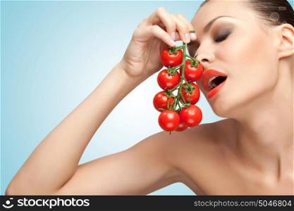 A creative portrait of a beautiful girl holding a bunch of cherry tomatoes near her mouth sexually.