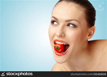 A creative portrait of a beautiful girl holding a cherry tomato sexually in her teeth.