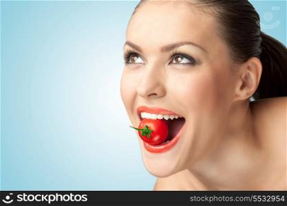 A creative portrait of a beautiful girl holding a cherry tomato sexually in her teeth.