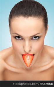A creative portrait of a beautiful girl holding a fresh strawberry in her sexy mouth like a tongue.