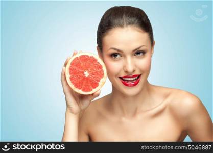 A creative portrait of a beautiful girl holding a red grapefruit sexually under her chin.