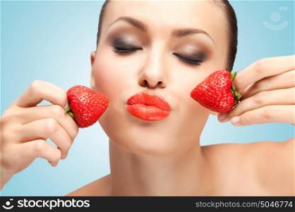 A creative portrait of a beautiful girl holding juicy strawberries near her lips with desire.