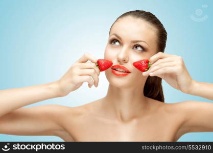 A creative portrait of a beautiful girl holding juicy strawberries near her lips with desire.