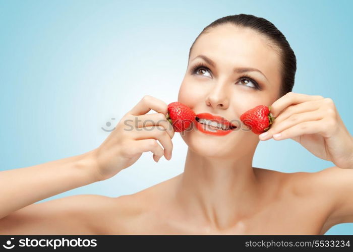 A creative portrait of a beautiful girl holding juicy strawberries near her lips with desire.