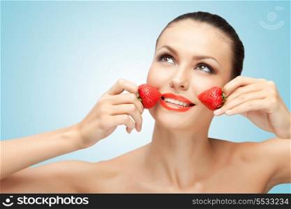 A creative portrait of a beautiful girl holding juicy strawberries near her lips with desire.