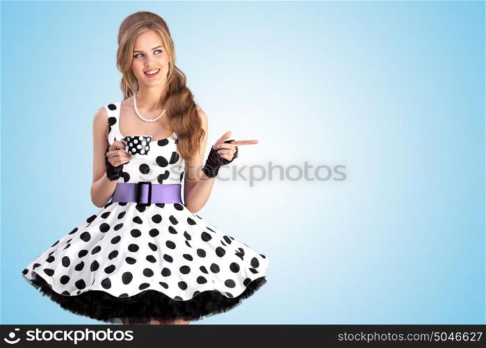 A creative vintage photo of a beautiful pin-up girl in a polka dot dress holding a cup of tea.