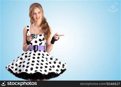 A creative vintage photo of a beautiful pin-up girl in a polka dot dress holding a cup of tea.