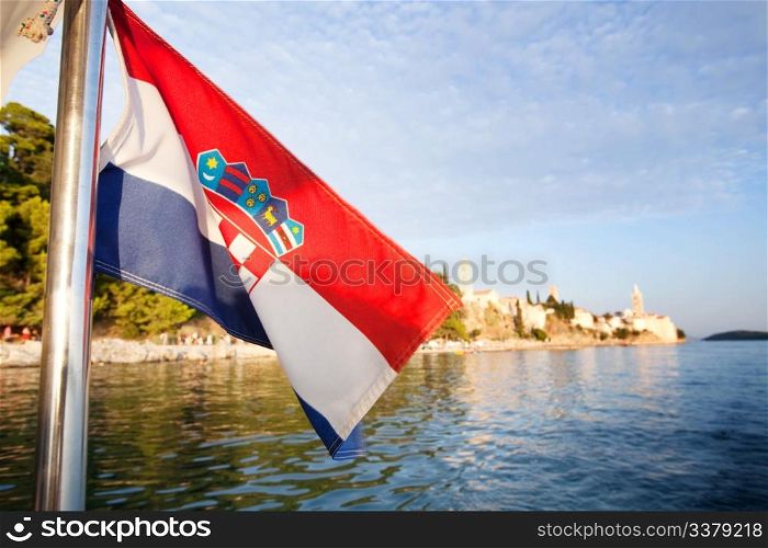 A croatian flag in front of a landscape of the island of Rab