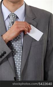 A cropped picture of a businessman putting his card in his pocket.